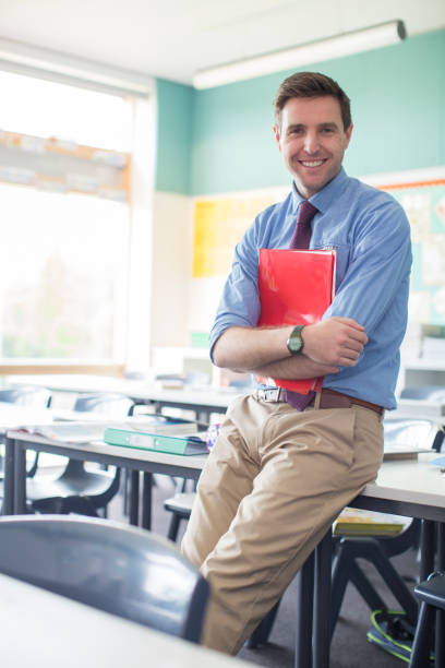 ritratto dell'insegnante sorridente appoggiato alla scrivania in classe - giacca e cravatta foto e immagini stock