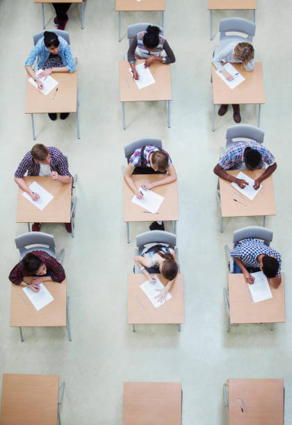 Large group of students sitting in the classroom and writing a test.