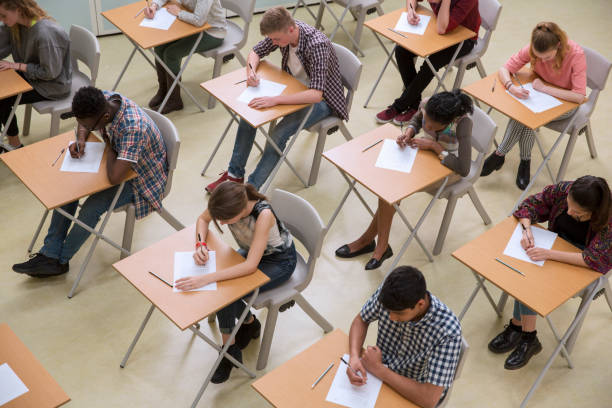 erhöhte sicht auf studenten, die ihre gcse-prüfung schreiben - schulische prüfung stock-fotos und bilder