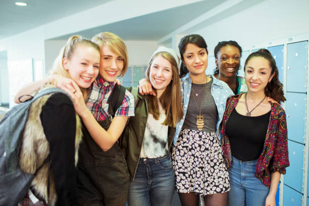 Group portrait of cheerful female students standing in locker room  female high school student stock pictures, royalty-free photos & images