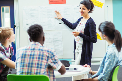 Business coach conducting training of businesspeople. African female professional discussing with audience and writing on flipchart during a seminar.