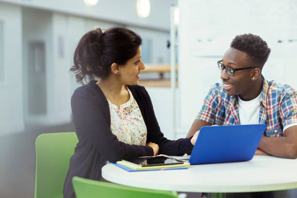 ラップトップとタブレットと一緒に座っている教師と学生 - african descent male education indoors ストックフォトと画像