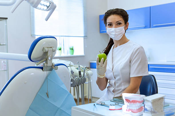 istock Dentist in mask holding green apple. 525419575