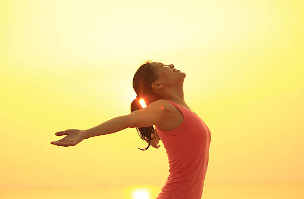 istock cheering woman open arms to sunrise at seaside 525420577