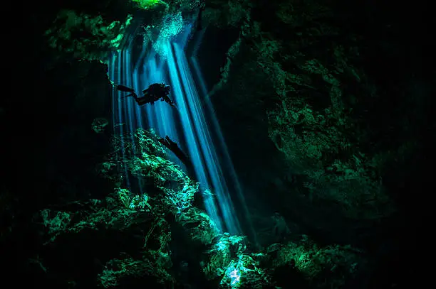 Scuba diver exploring the underwater cenotes in Mexico near Puerto Aventuras. Caves are dark and the light always gives different amazing ambient underwater.