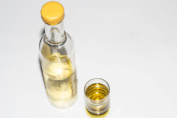 Bottle and Glass of Alcohol on White.