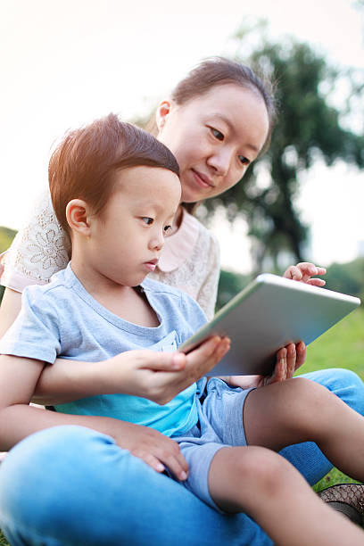 istock happy mother teaching little boy with tablet 525432597