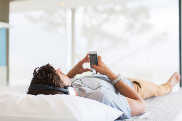 istock Man listening to music while lying on bed 525440113