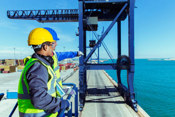istock Worker and businessman examining cargo crane at waterfront 525440479