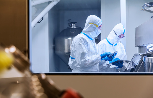 Científicos con trajes limpios usando tabletas digitales en experimentos en laboratorio photo