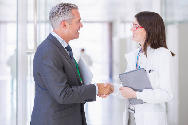 istock Scientist and businessman shaking hands in hallway 525440821