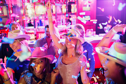 Confetti falling on women in cowboy hats dancing in nightclub
