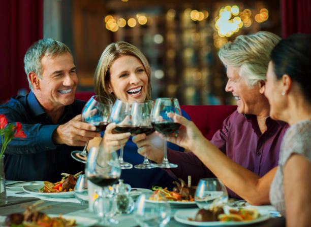 leute, die mit rotwein im restaurant anstoßen - restaurant tablecloth stock-fotos und bilder