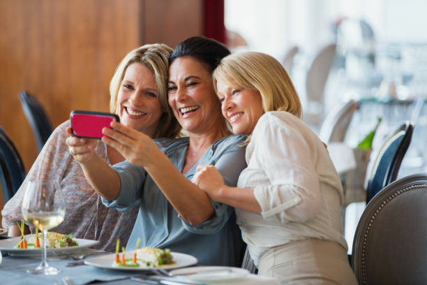 레스토랑에서 셀카를 찍는 세 성숙한 여성 - women friendship beautiful mature women 뉴스 사진 이미지