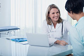 istock Smiling female doctor and woman sitting at desk in office 525441395
