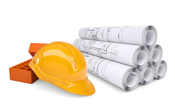 istock Scrolls of architectural drawings and building bricks with helmet 525449205