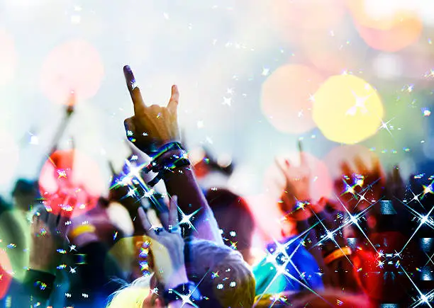 Photo of concert crowd in front with hands up with rock-n-roll sign