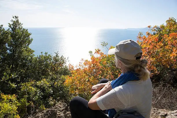 Photo of Woman looks out from treed knoll to sea