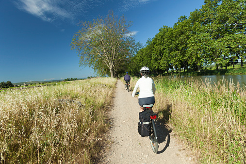 Woman and man cycling on path near river on the canal du midi in France.
