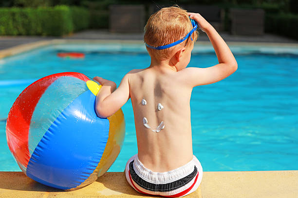 garçon avec ballon de plage coloré sur la piscine - beach ball swimming pool ball child photos et images de collection
