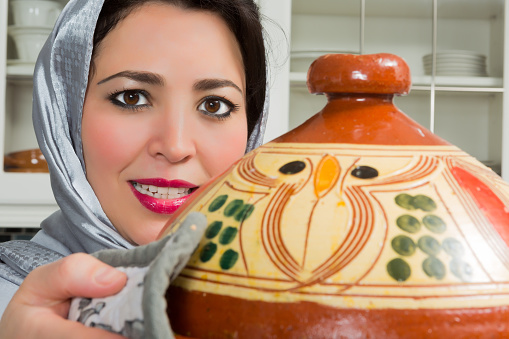 Moroccan immigrant woman in Europe presenting her tajine dish during Ramadan in her modern kitchen