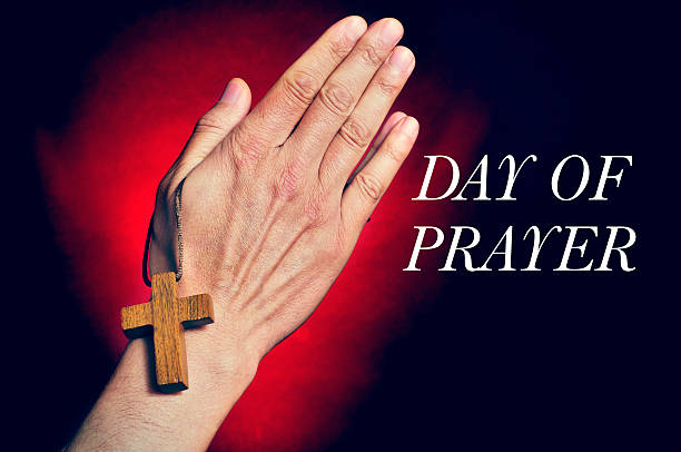 man praying and text day of prayer closeup of a young caucasian man praying with a wooden cross in his hands and the text day of prayer national day of prayer stock pictures, royalty-free photos & images