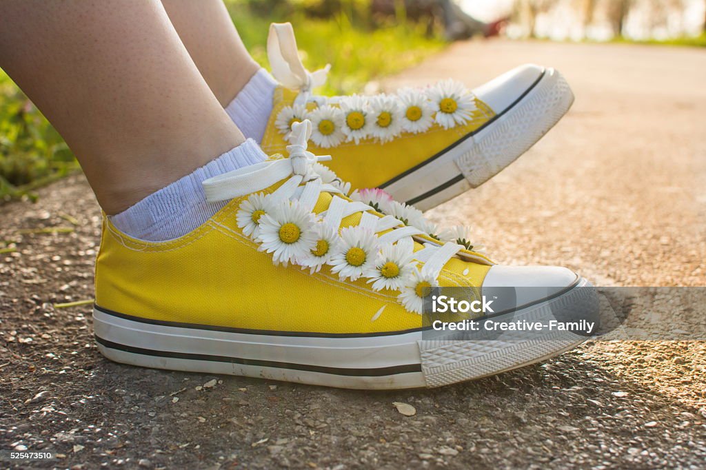 Gelbe Sneaker mit Gänseblümchen - Lizenzfrei Asphalt Stock-Foto