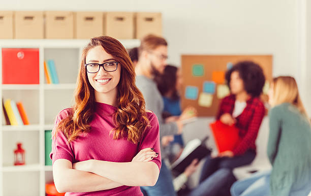 College student with crossed arms looking at camera Smiling woman in the classroom teacher sucess stock pictures, royalty-free photos & images