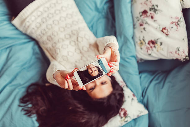 istock Smiling woman taking selfie in bed 525482494