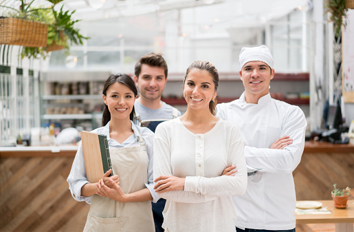 Staff working at a restaurant and looking at the camera smiling - small business concepts