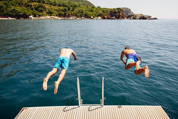 istock men jumping into sea water from yacht 525487922