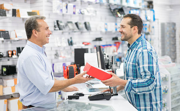 Man shopping at a tech store Casual man shopping at a tech store and talking to salesman over the counter electronics store stock pictures, royalty-free photos & images
