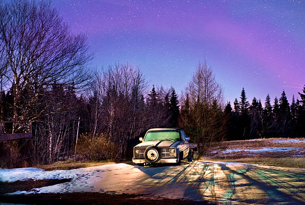 Old truck in a feild at night under starry sky.