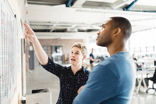 istock Businesswoman explaining to colleague on whiteboard 525494998
