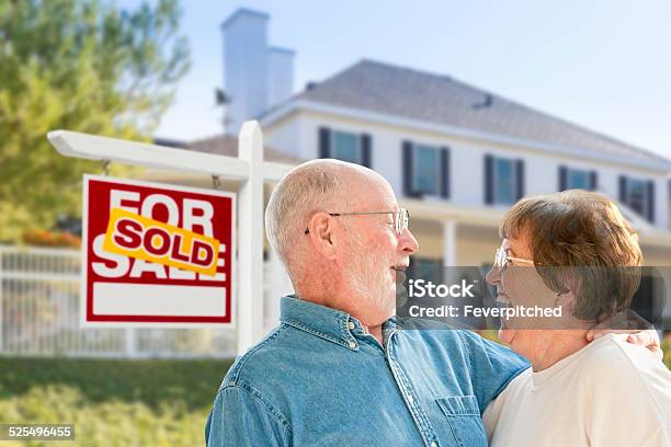 Senior Couple In Front Of Sold Real Estate Sign House Stock Photo - Download Image Now