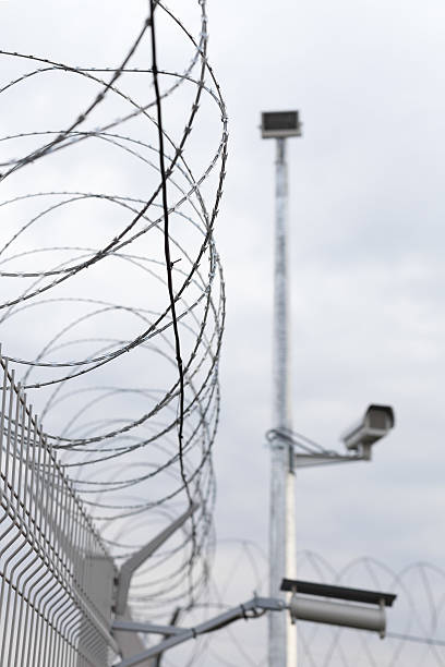 istock Barbed wire on the fence with security camera 525496505
