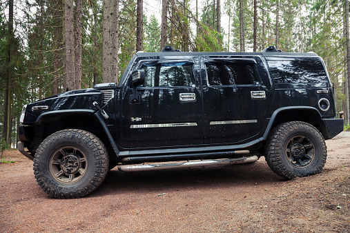 Saint-Petersburg, Russia - October 12, 2014: Black Hummer H2 vehicle stands on dirty country road in Russian forest, side view