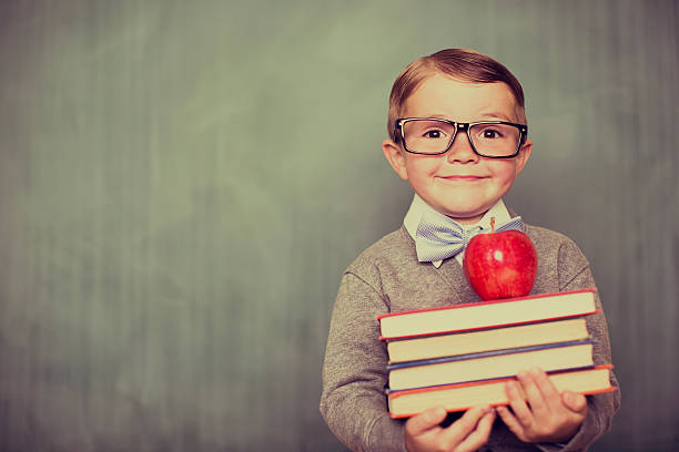 istock Young Retro Boy Holding Books in Classroom 525499257