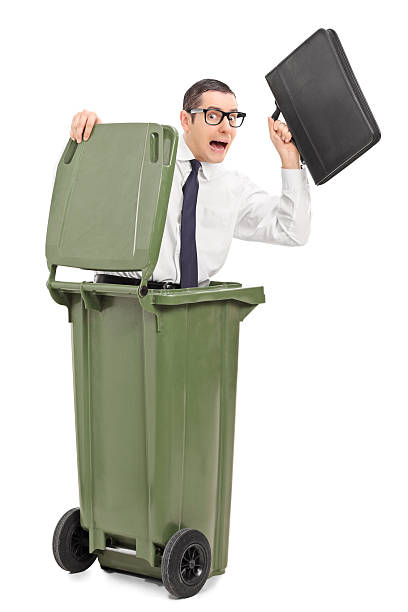istock Terrified businessman hiding in a trash can 525500639