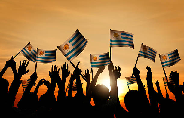 istock Group of People Waving Uruguayan Flags in Back Lit 525501339