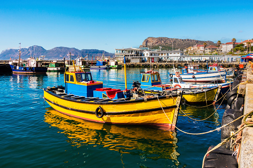 Yellow fishing boat at Kalk Bay harbour, a fishing village in False Bay, Cape Town, South Africa. Fresh fish available at the harbour where many tourists come to buy.