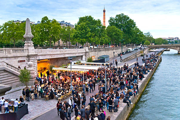Group of young people relaxing, drinking and having fun next to the River Seine near Pont Alexandre III bridge 