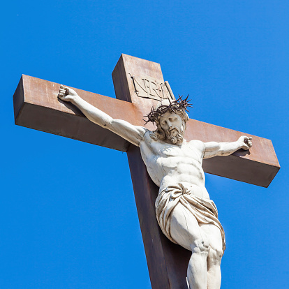 Crucifix made of marble with blue sky in background. France, Provence Region.