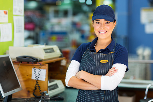 happy female hardware store cashier with arms folded