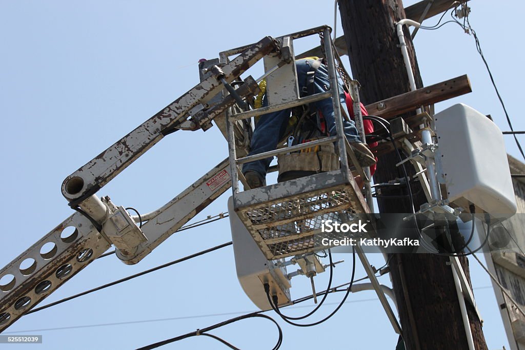 Electrical Contractor Repairman Electrical contractor repairman on hydraulic lift making electrical repairs. Blue-collar Worker Stock Photo