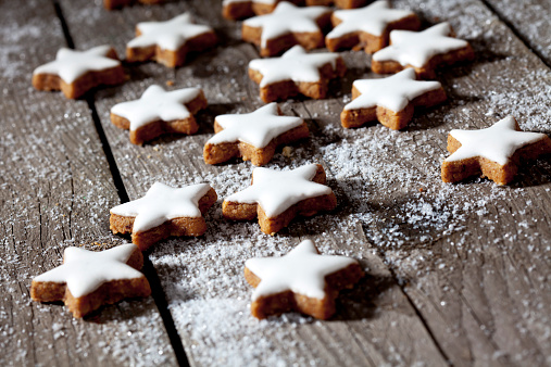 Cinnamon stars with powder sugar on wooden background close up.