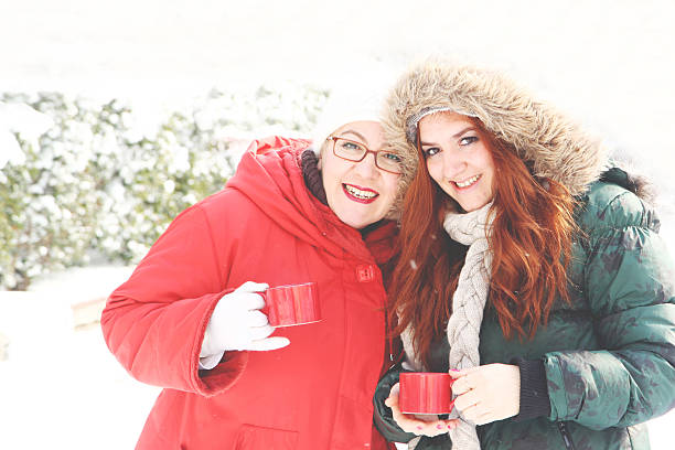 Due donne di età media brindando con caffè caldo - foto stock