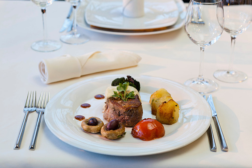 Elegance decorated Meat mignon with potato, tomato and olives on plate in restaurant.