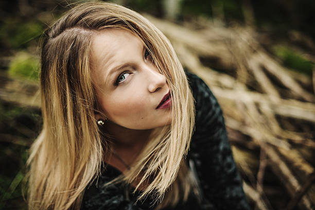 Young teenage smiling girl with blonde long hair, red lips and blue eyes looking at camera.