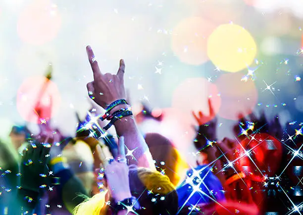 Photo of concert crowd in front with hands up with rock-n-roll sign